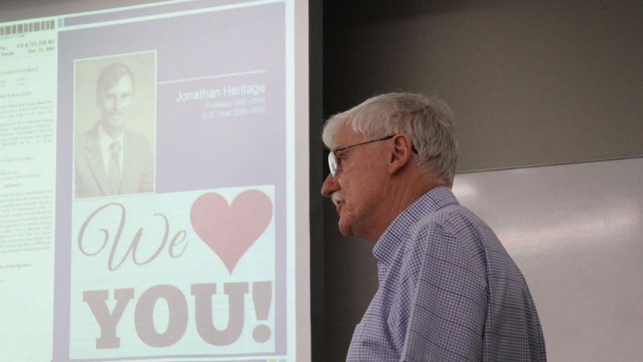 Jonathan Heritage, foreground, with PowerPoint slide behind him, reading "Jonathan Heritage: We Love You."