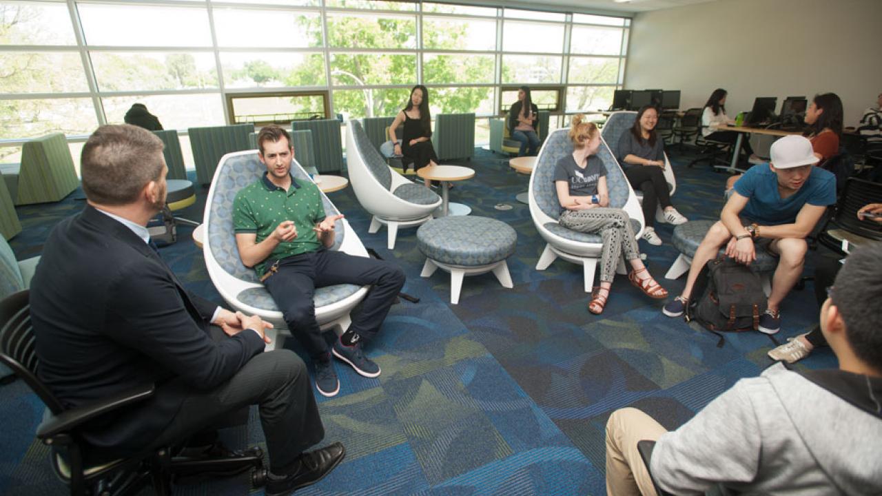 Visitors and international students and scholars sit in a semicircle.