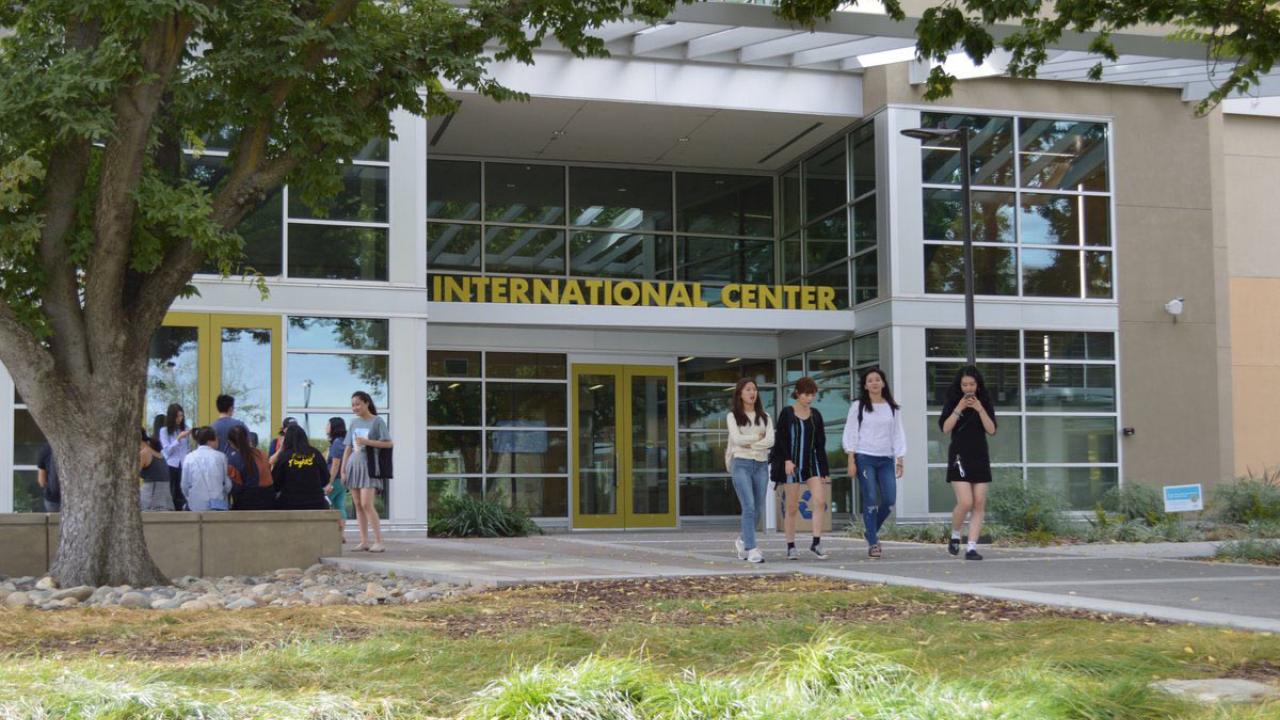 Four people walk near the entrance to the International Center.