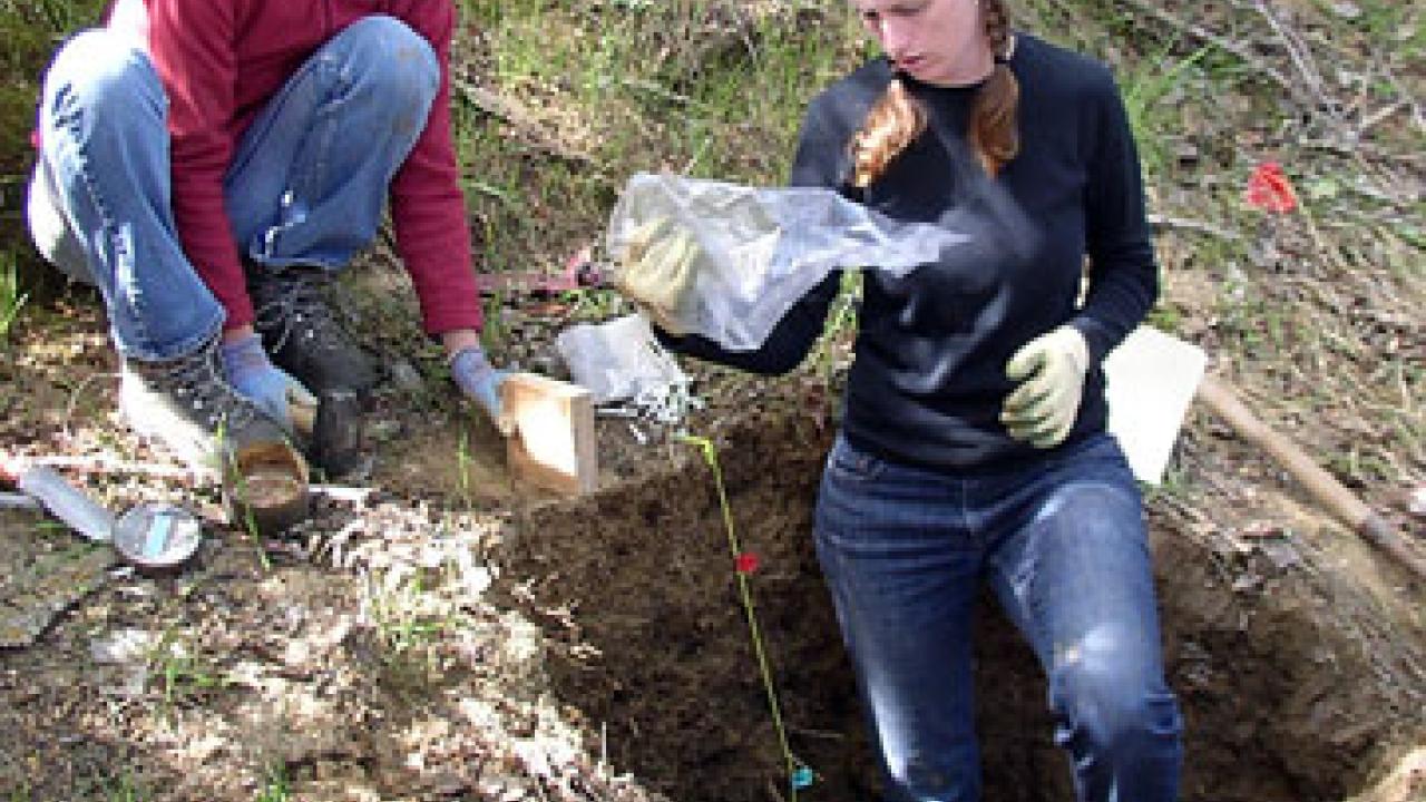 Photo: two women out doors examining soil in bag