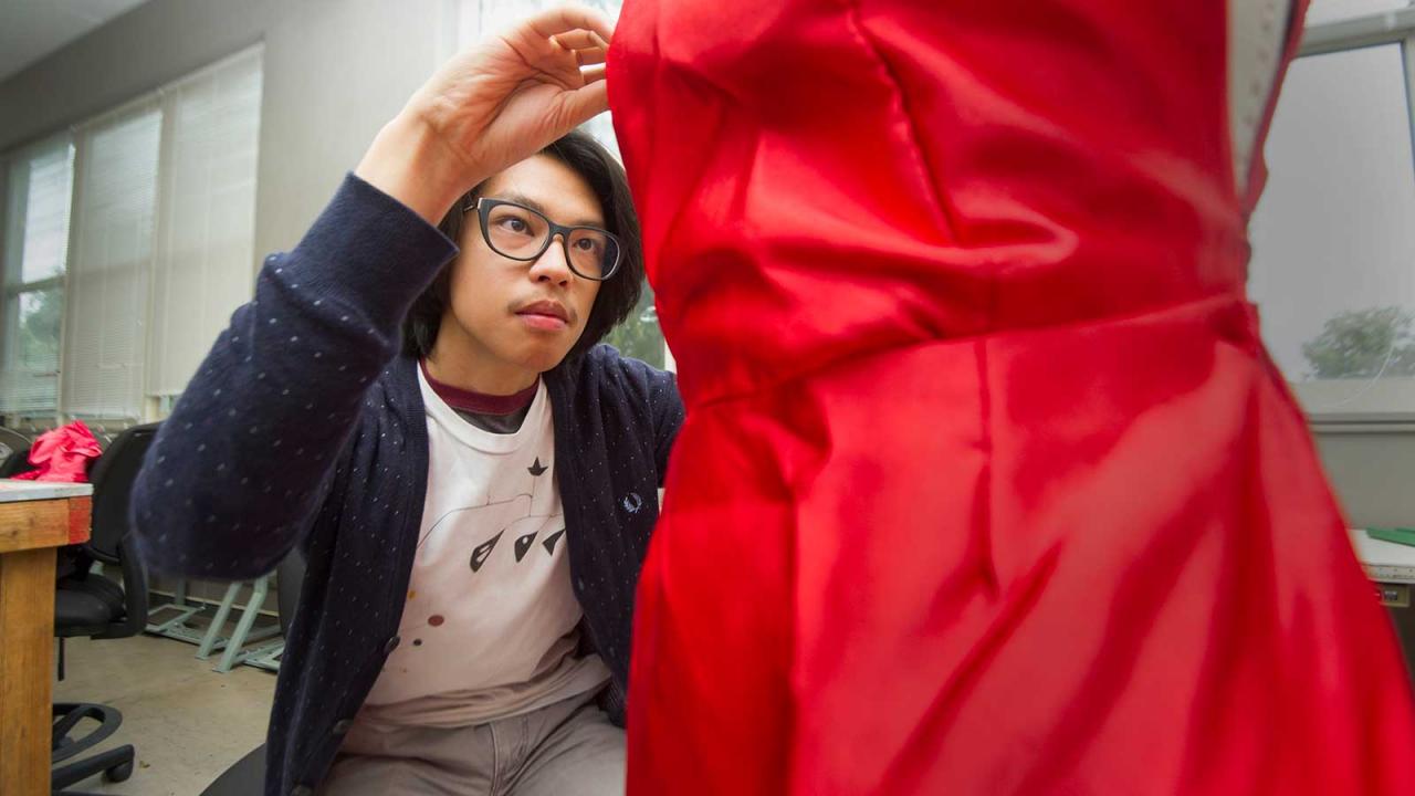 Jason Lin adjusts his red dress on a mannequin