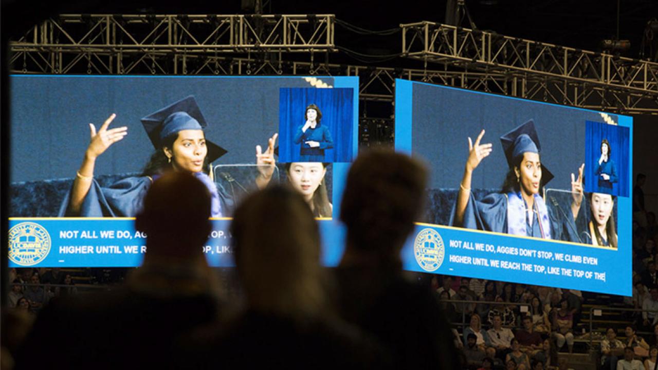 Two jumbo screens show a student rapping her commencement speech. (David Slipher/UC Davis)