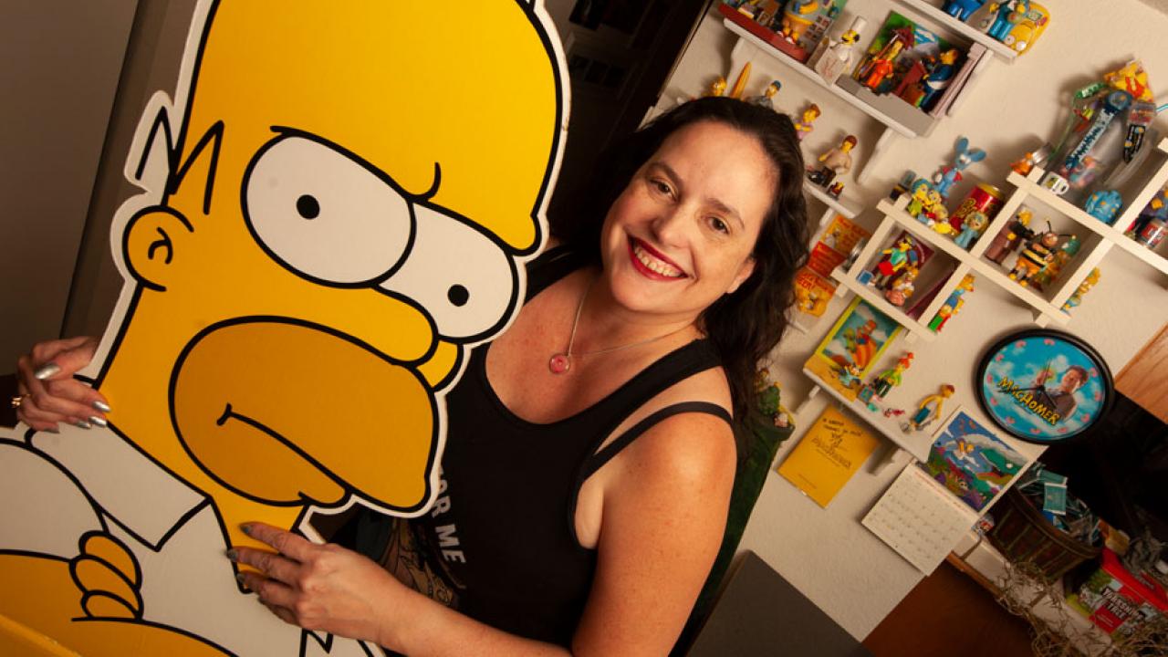 Karma Waltonen poses with larger-than-life-size cardboard cutout of cartoon character Homer Simpson.