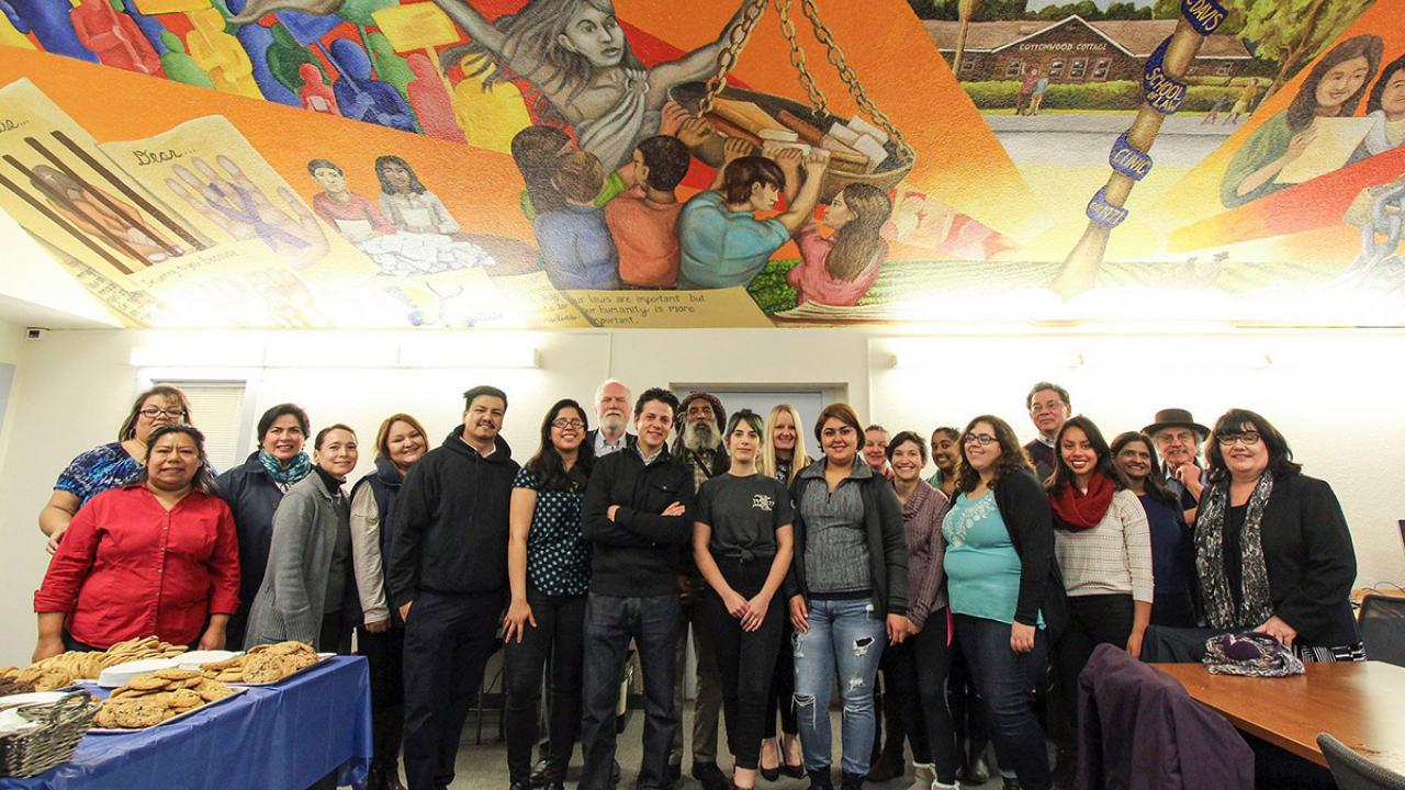Students, faculty and staff pose under a mural.