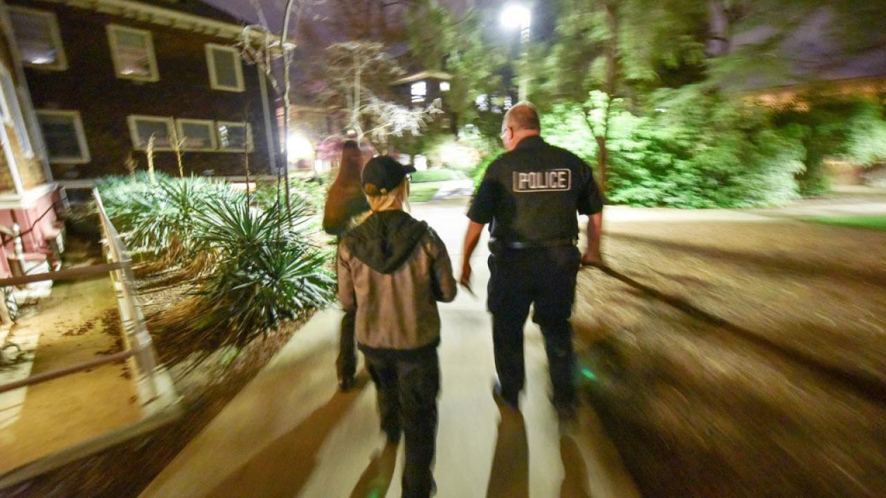 Students and police, walking, at night, on campus.