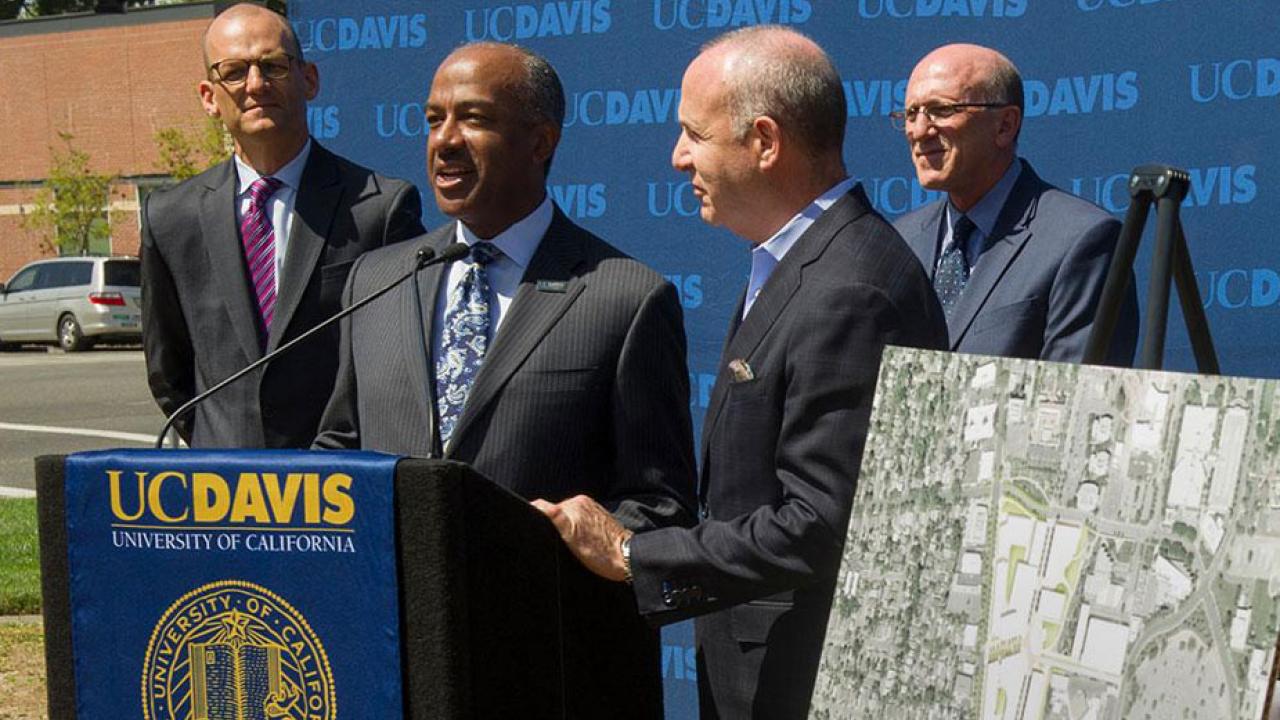 Gary S. May and Darrell Steinberg at podium adorned with UC Davis banner (with seal)