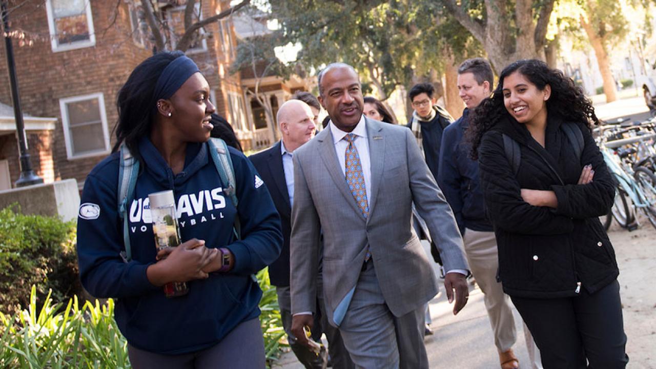 Chancellor Gary S. May flanked by student assistants
