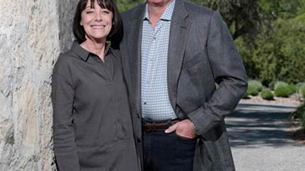 Woman and man standing next to an adobe wall outside