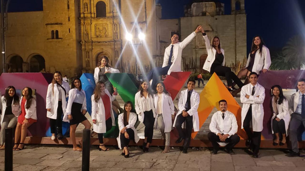 Students in white coats, posing at night in Oaxaca.