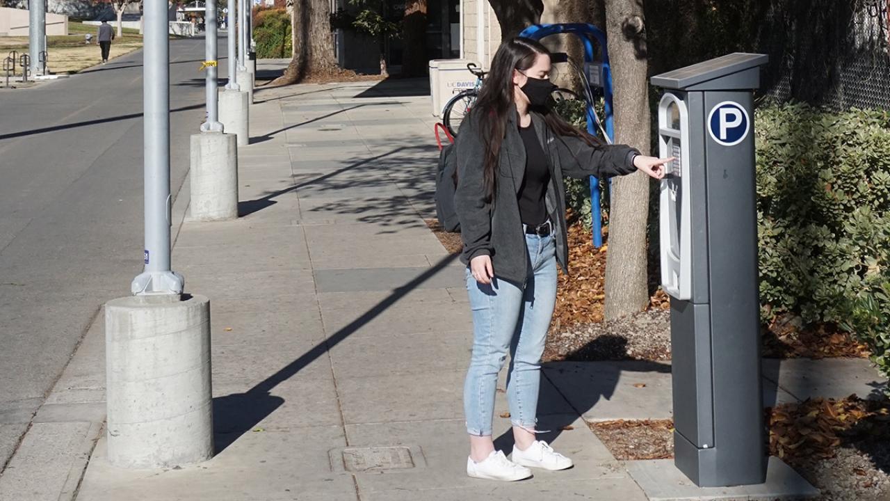Woman uses parking kiosk.