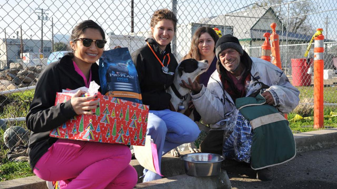 Volunteers give Holiday Pet Basket to man and his dog.