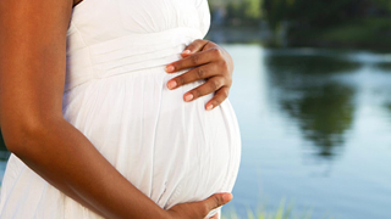 Cropped photo of a pregnant woman standing near a lake