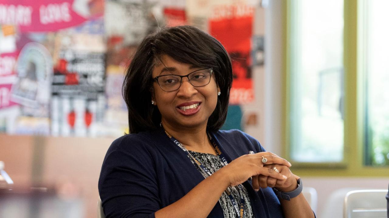 Renetta Garrison Tull, hands clasped, at meeting, smiling.