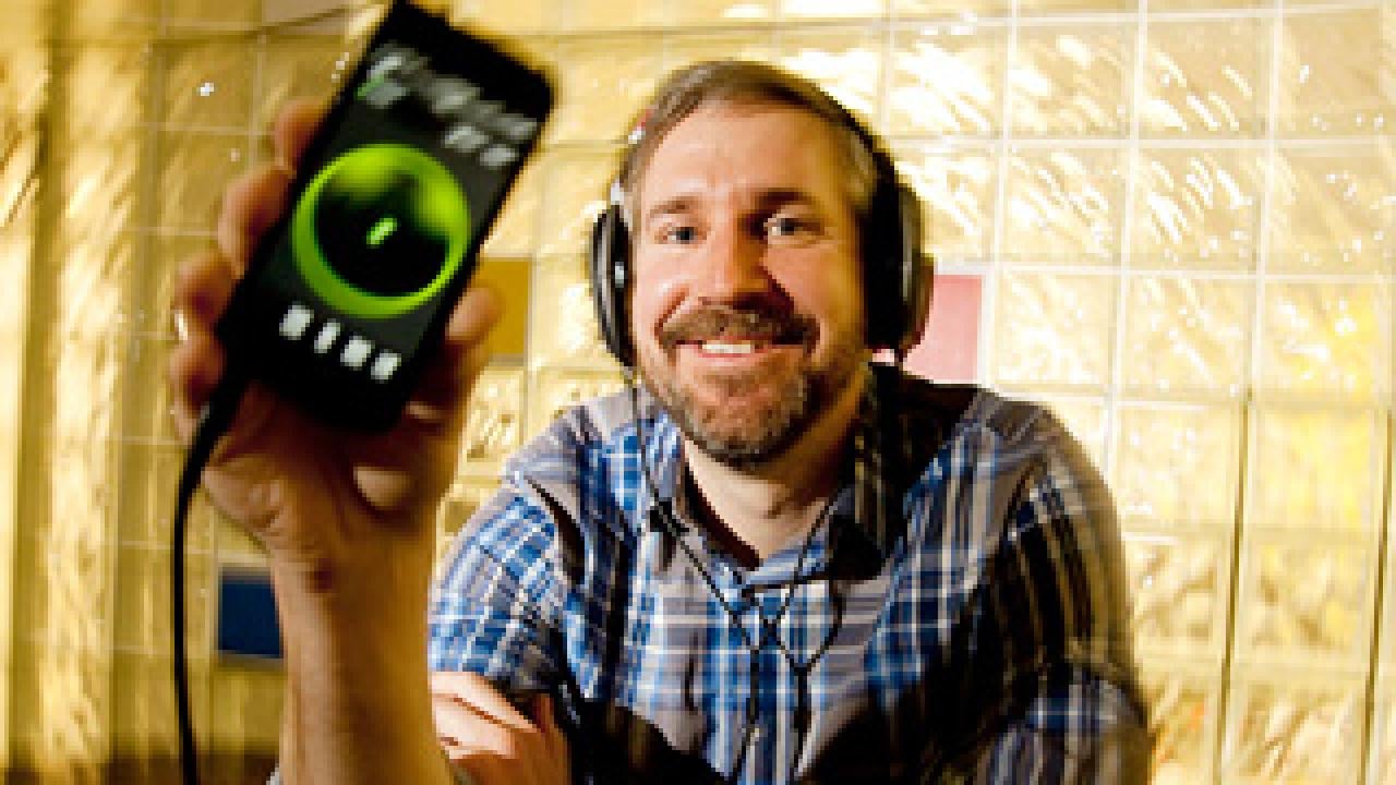 Man in earphones holding an electronic device with a lit green circle in the middle