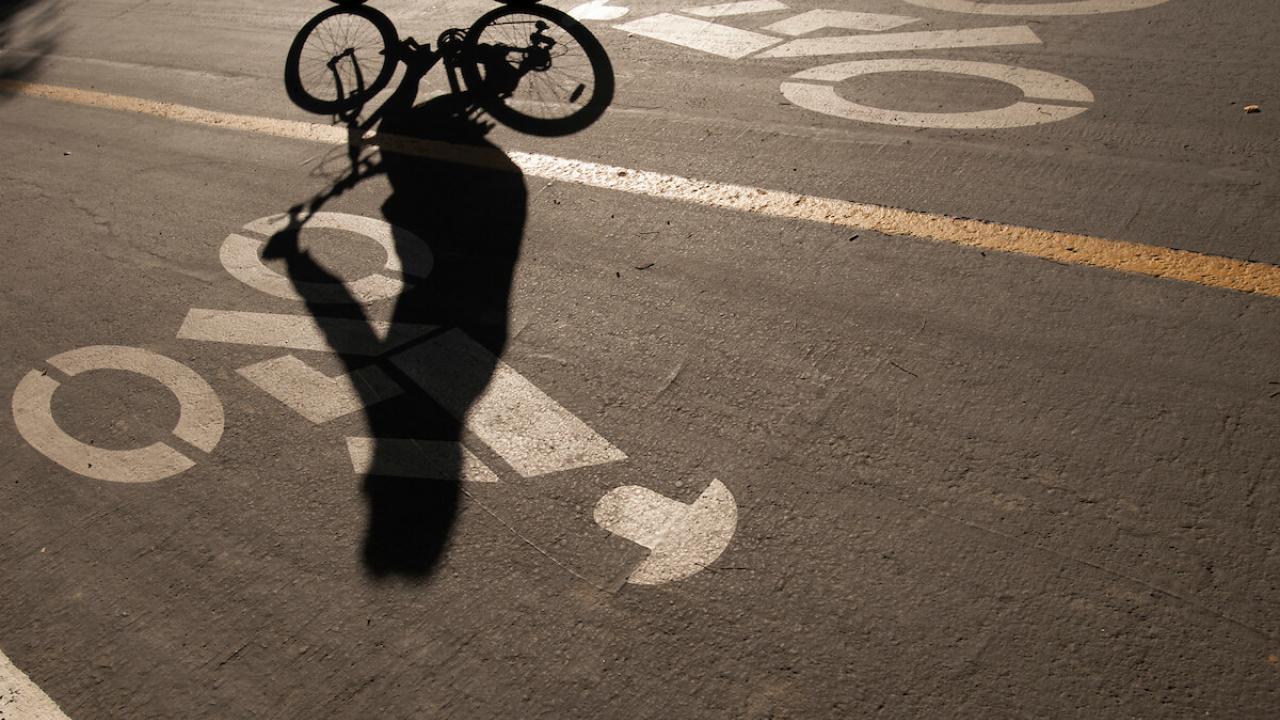 A student's shadow is seen on a bike path.