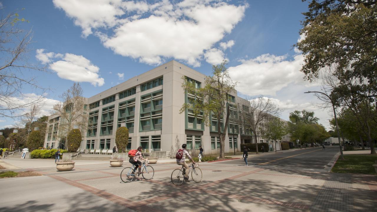 Students ride bicycles past Shields Library.