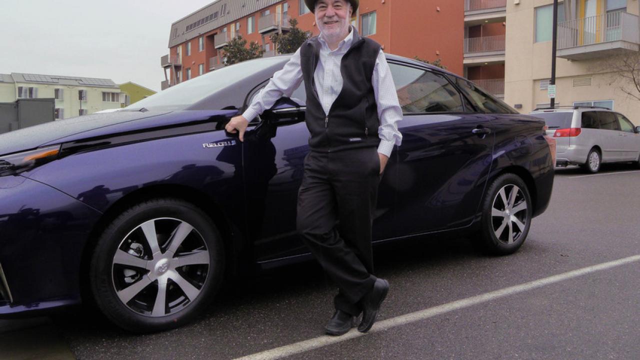 Male scientist stands with hydrogen fuel cell vehicle