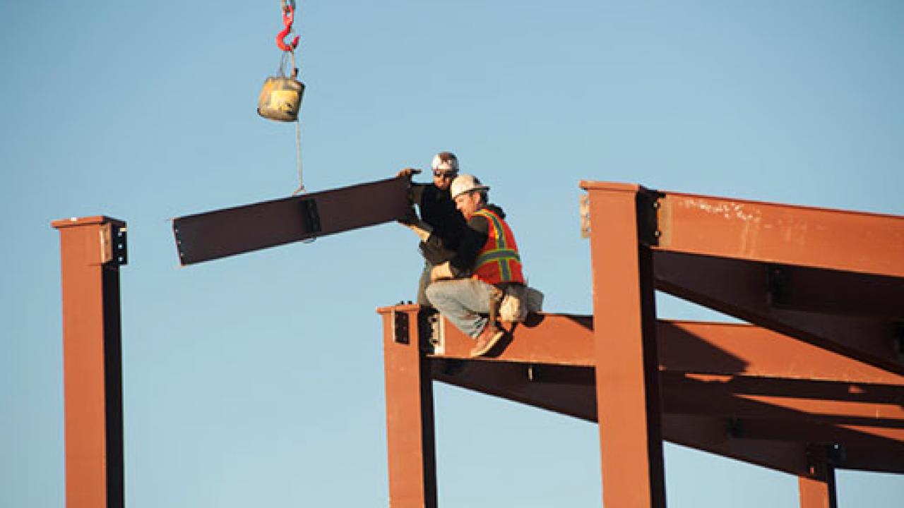 Steelworkers assemble the steel I-beams on a building