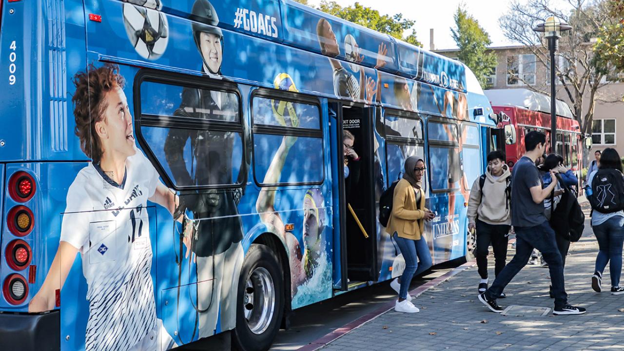 A bus decorated with photos of UC Davis athletes.