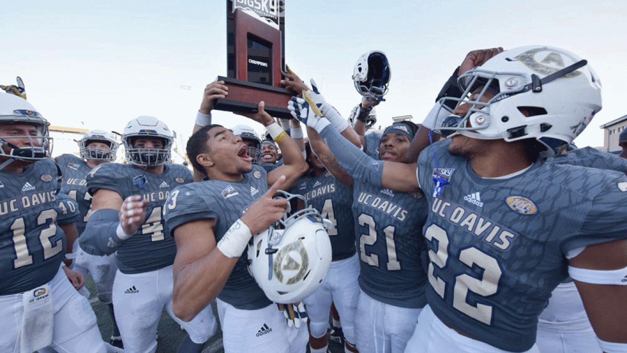 Aggie football team holds up Big Sky Conference trophy.