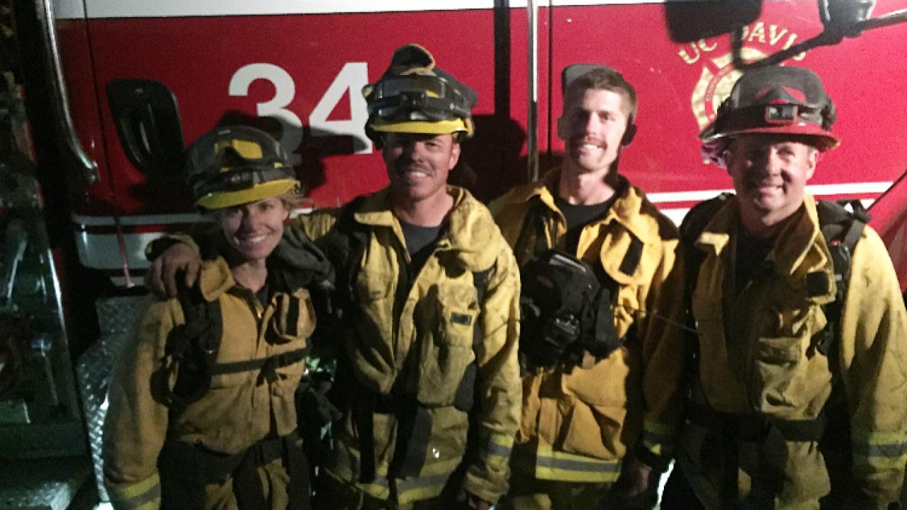 Four firefighters in front of a truck.