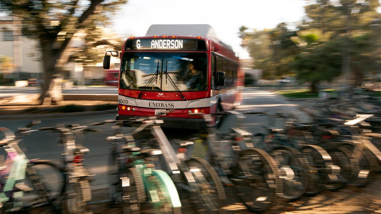 A Unitrans bus drives by rows of parked bicycles.