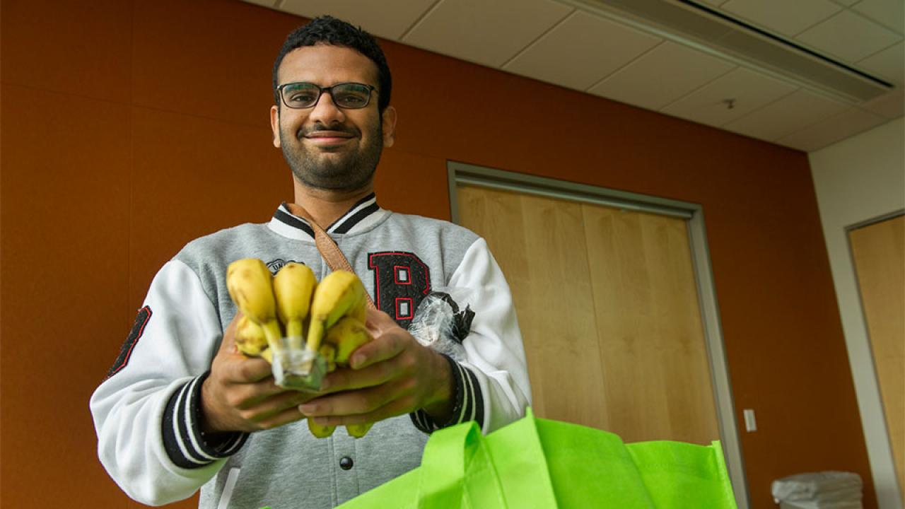 A male student holds a bunch of bananas