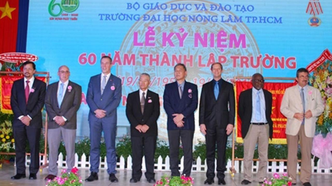Photo: Ceremonial photo, with group standing in front of colorful banner