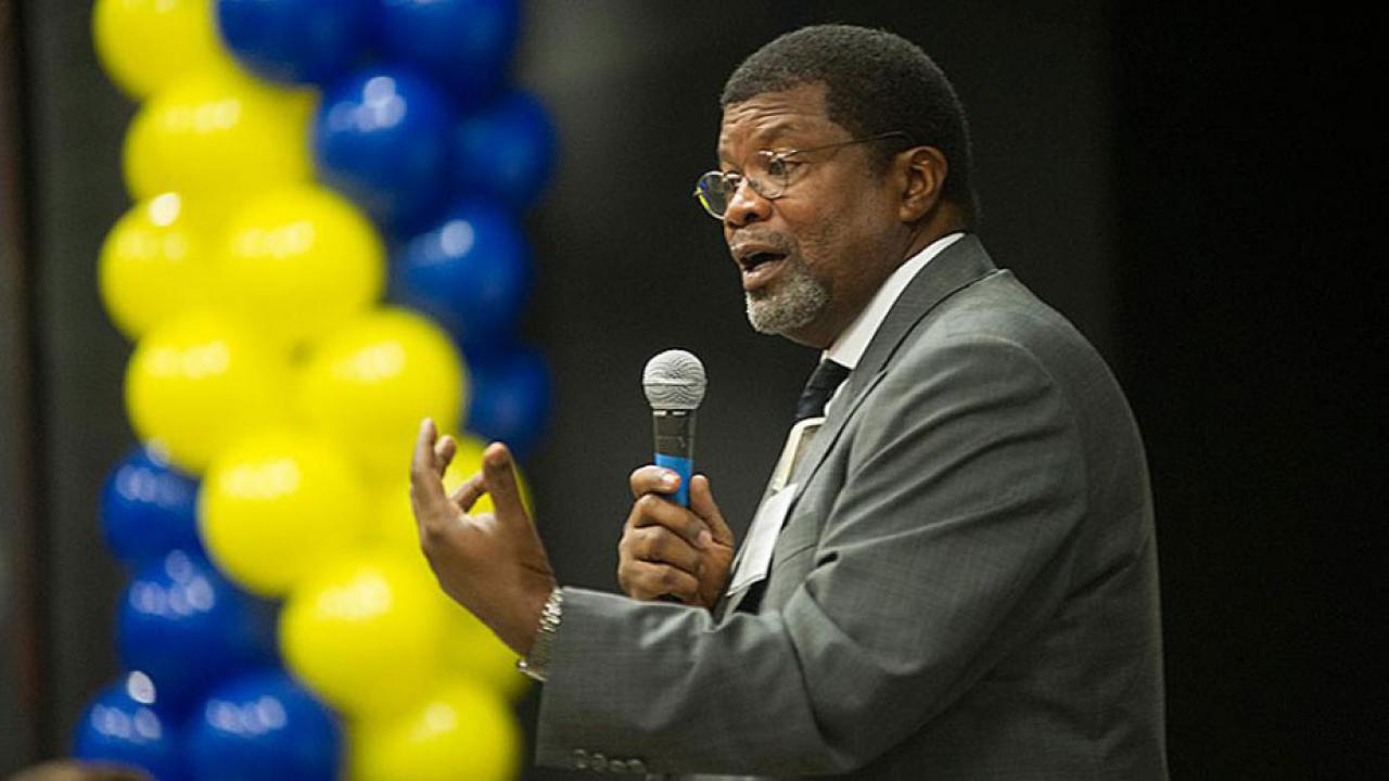 Walter Robinson with microphone, with blue-and-gold balloons in background