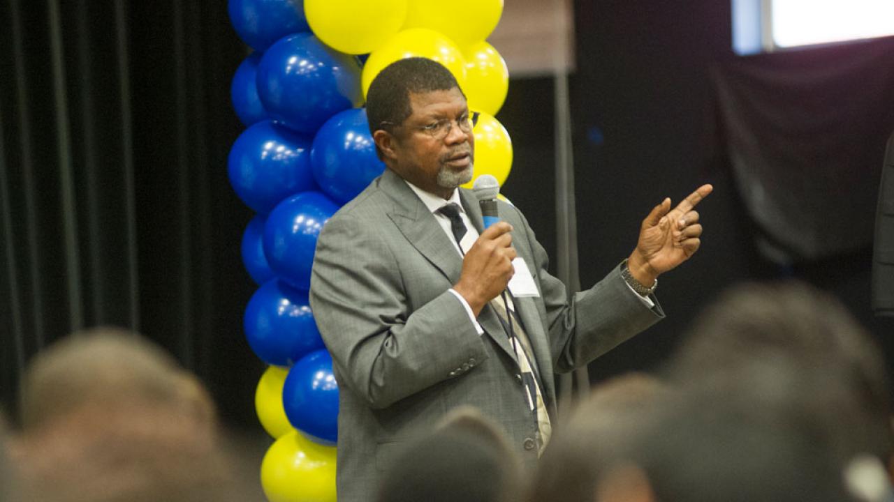 Walter Robinson addresses UC Achieve, with backdrop of blue-and-gold balloons.