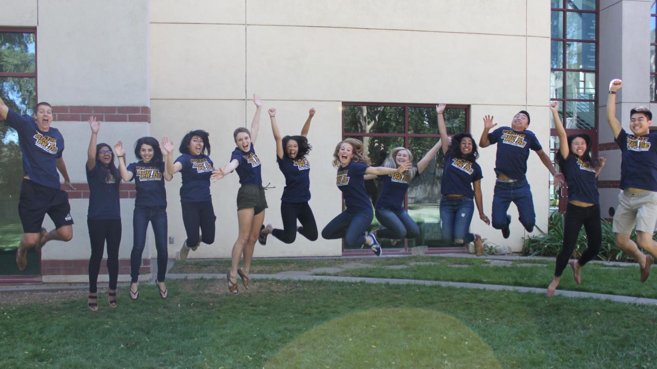 Twelve students jump up in front of a building