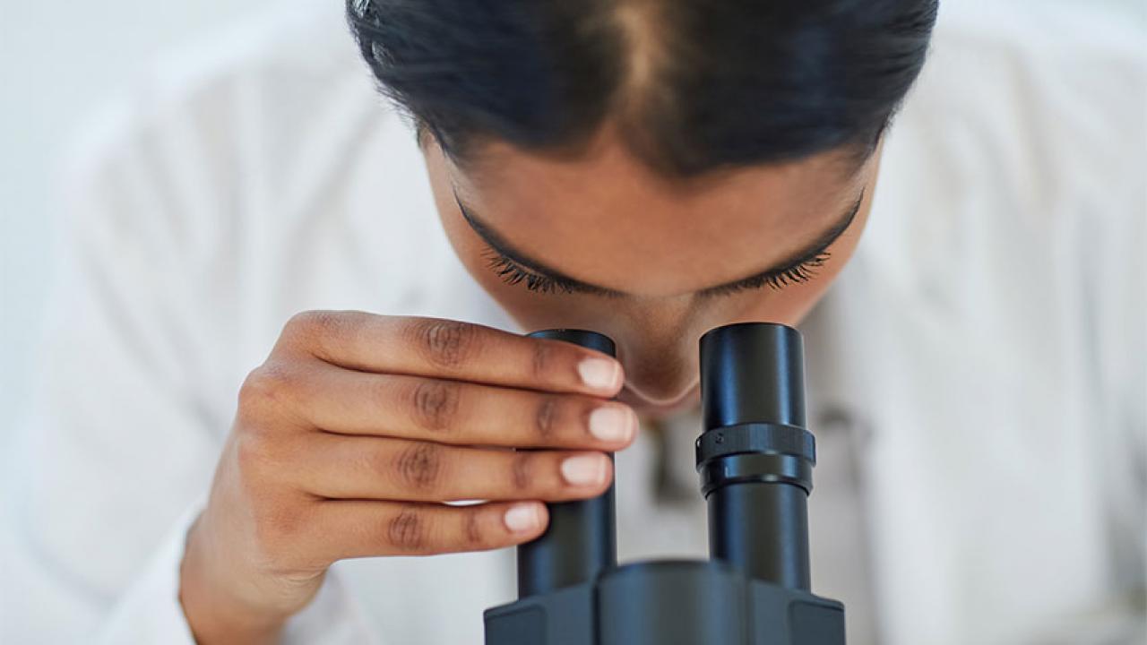 Closeup of woman looking in eye piece of scientific equipment