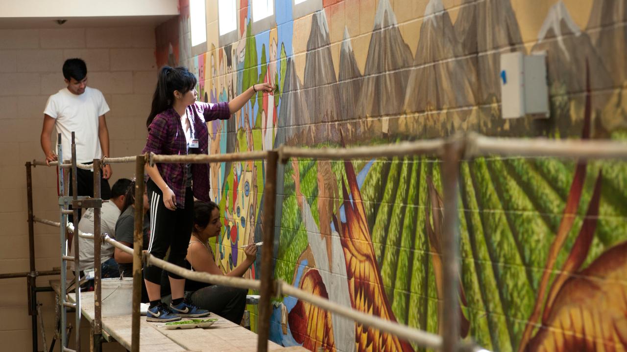 student painting a mural