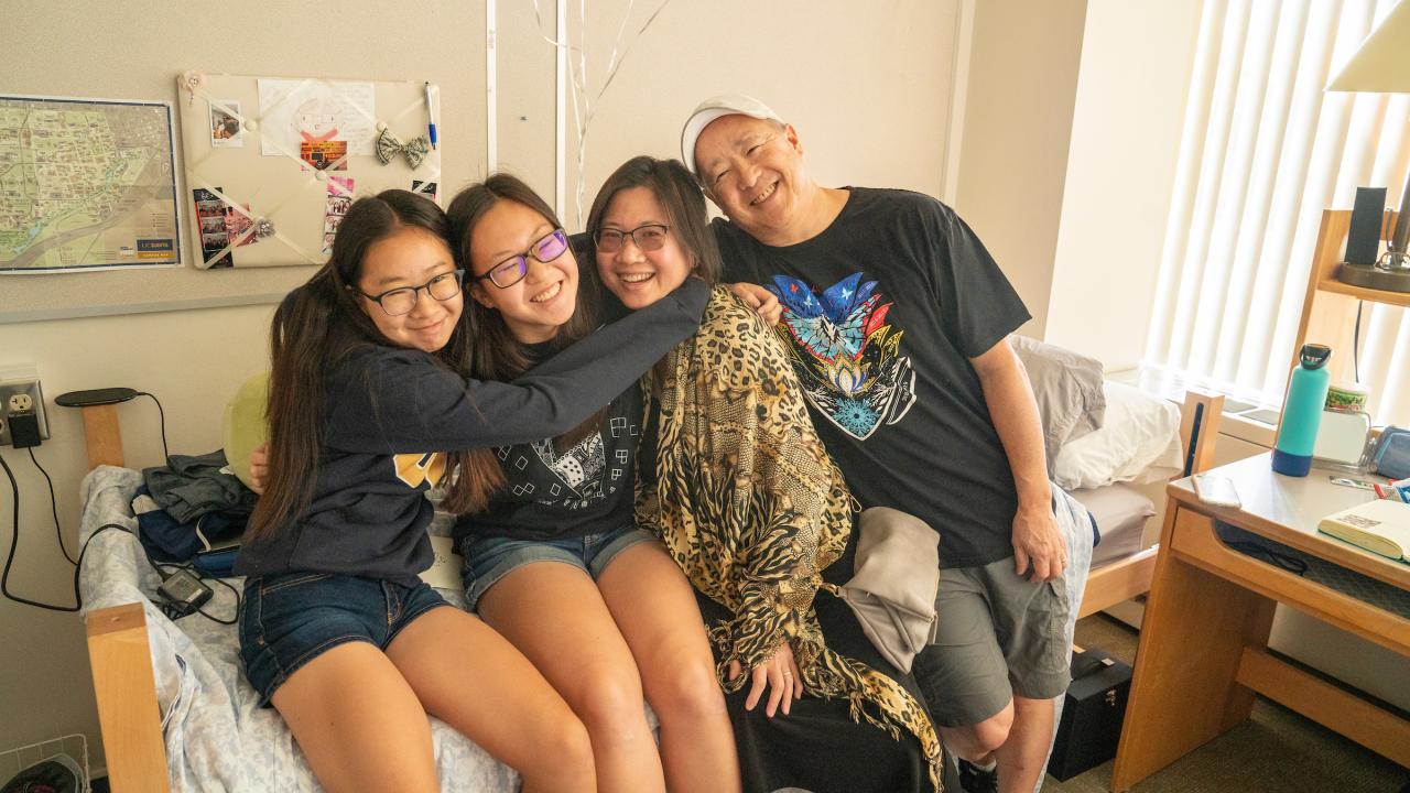 A father and his daughters hug in his daugthers new dorm room on move in day at UC Davis