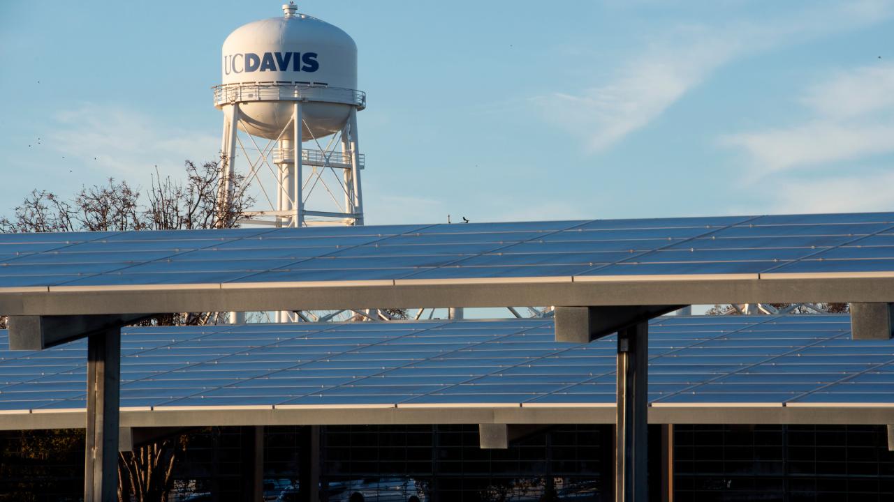UC Davis water tower rises above carport roofs covered in solar panels on campus