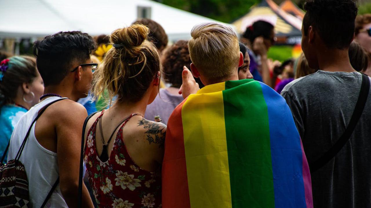 Group of young people, one wrapped in rainbow flag