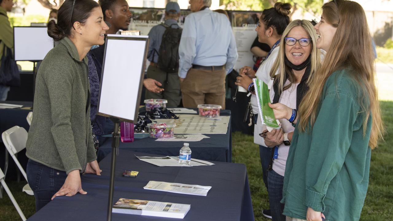 A student and parent talking with a campus representative at last year’s Aggie Day event.