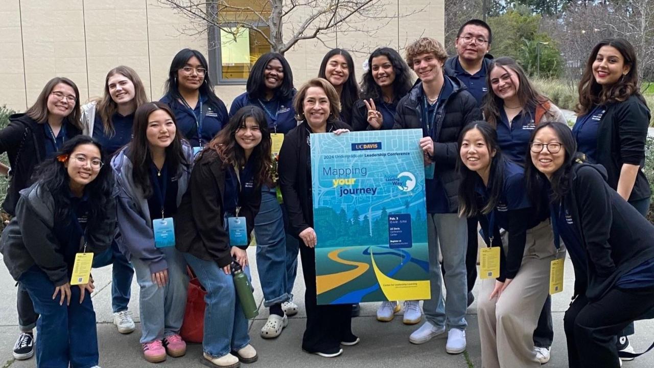 A group of students, Franchesca and Center for Leadership and Learning staff posing for a photo around a "Mapping your journey" poster outside of the UC Davis Conference Center.