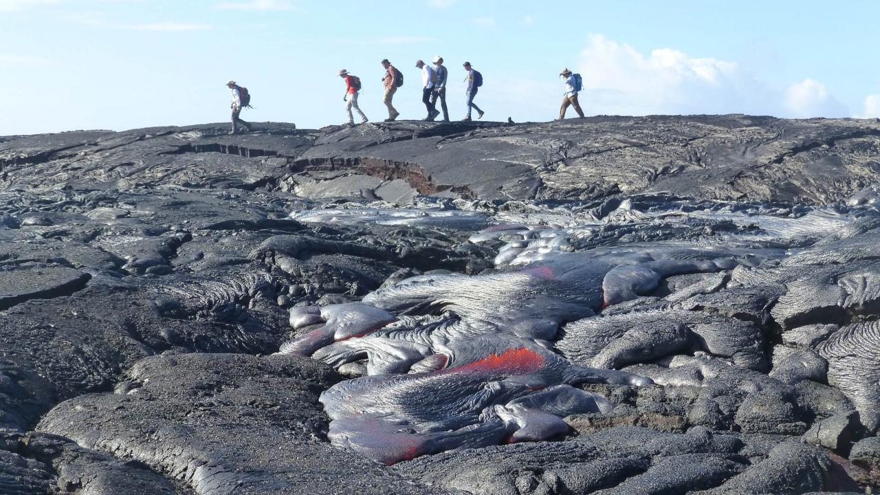Hikers in background crossing a lava field. 