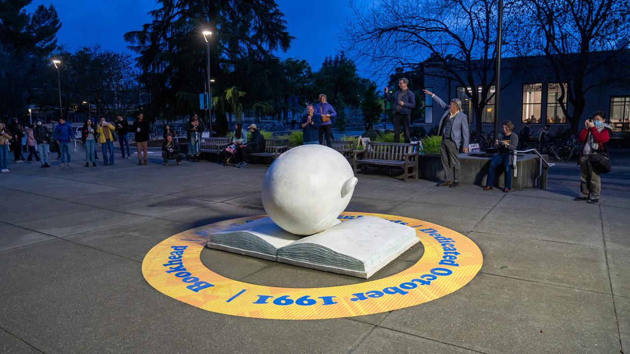 The Bookhead is lit from above at dusk and encircled by a large yellow sticker commemorating its 30th anniversary.