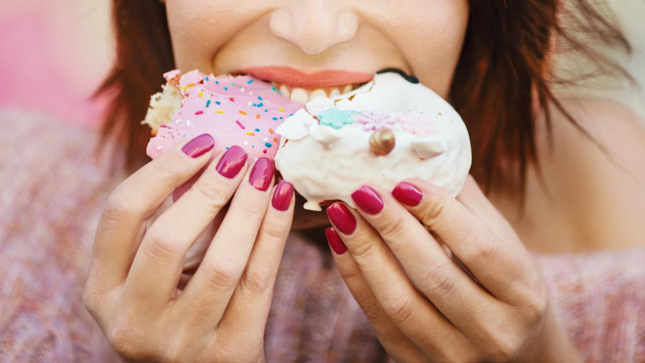 Woman's face visible from the nose down, as she eats two cupcakes