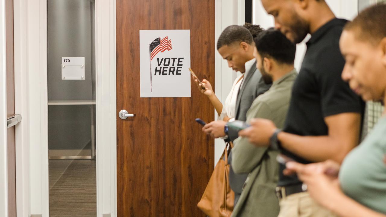 Voters in line to vote while looking at phones