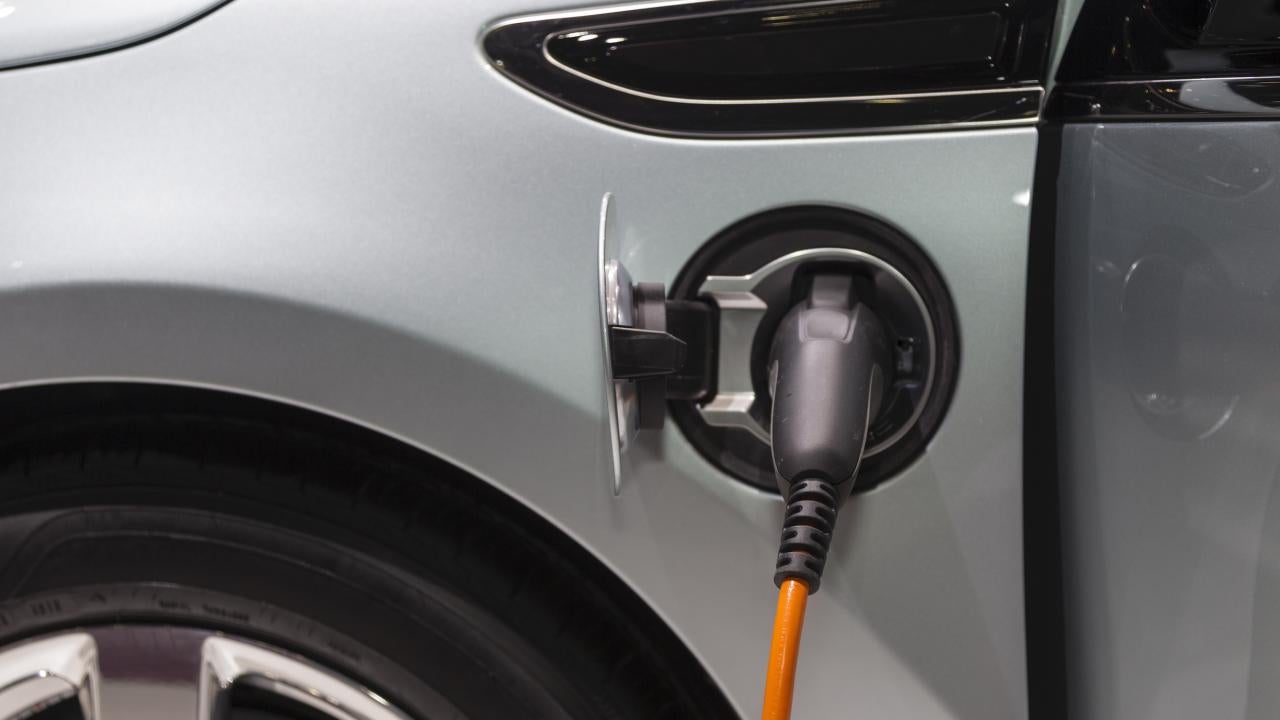 Electric vehicle plugged in and charging, gray