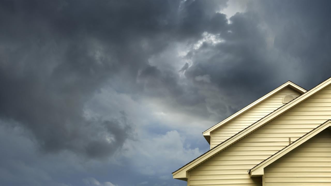 storm clouds hover over top of cream-colored home