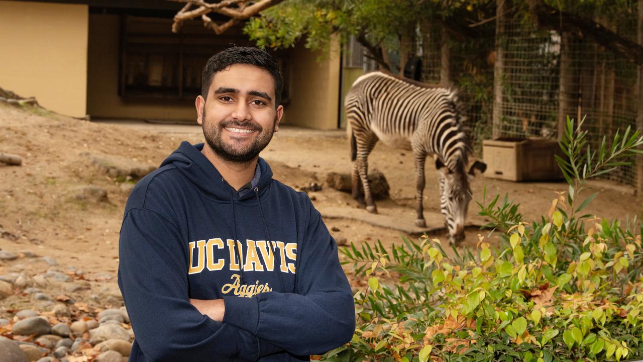 Jeevan Mann poses with a zebra in the background at the Sacramento Zoo
