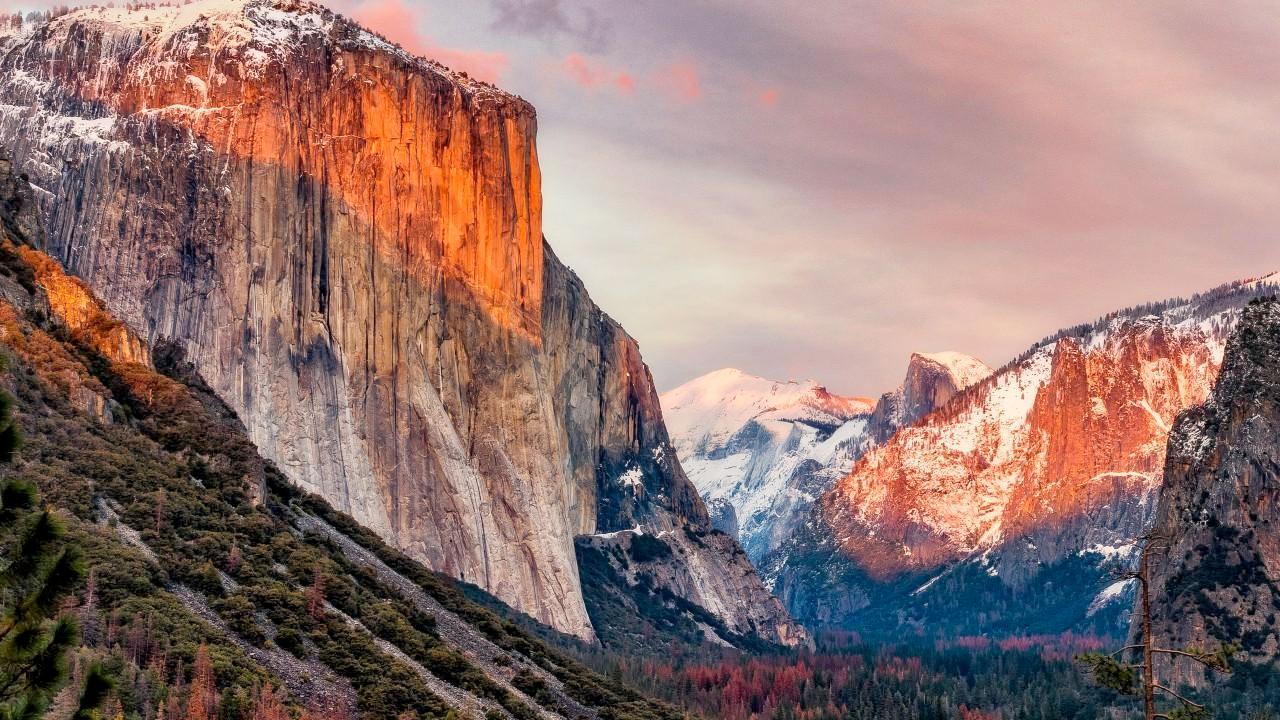 A beautiful landscape view of Yosemite valley with its rising cliffs and falling waterfalls all wrapped in a warm sunset.