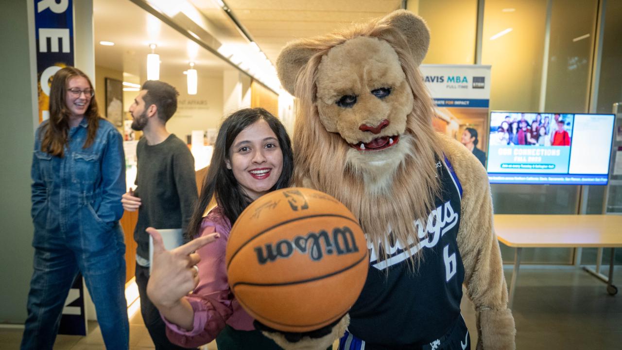 Woman holds basketball posing next to Kings mascot