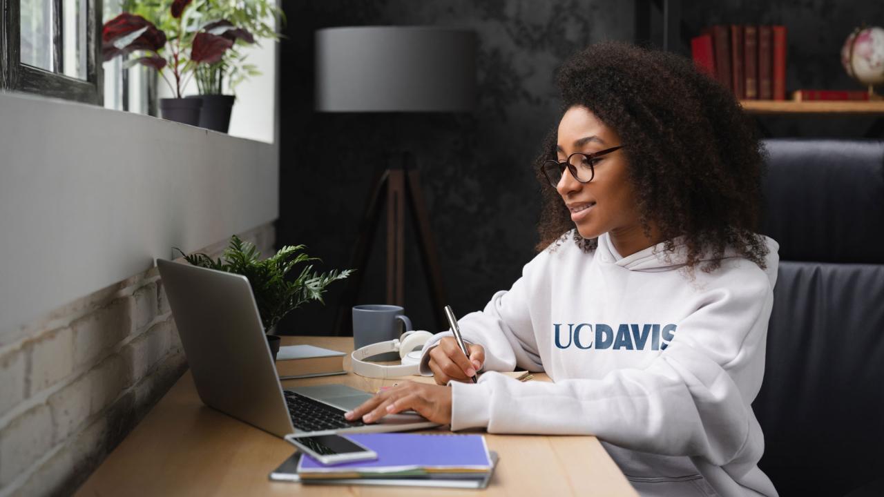 Woman with UC Davis shirt working at laptop computer