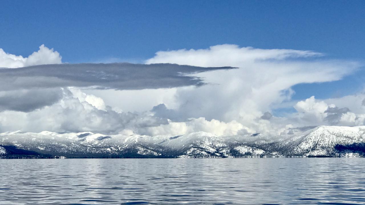 Lake Tahoe with snow-capped mountains in background under winter clouds
