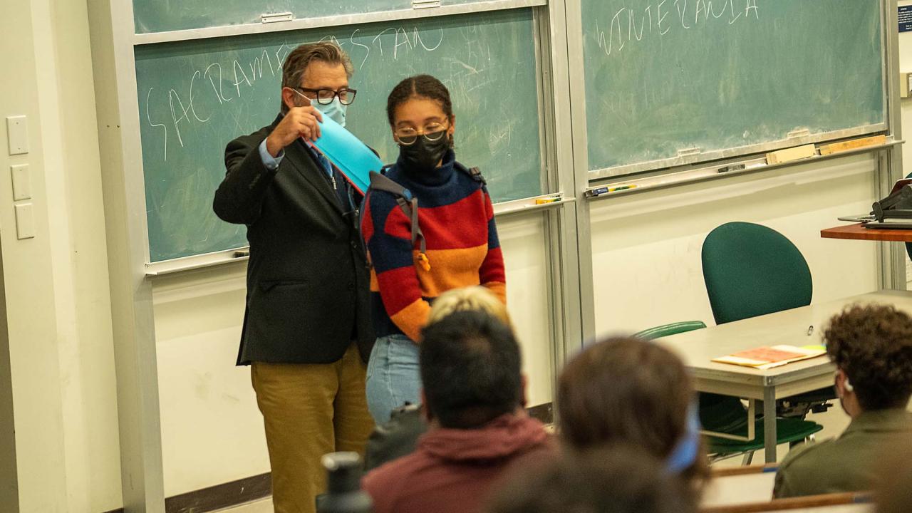 A professor puts a symbolic card into a student's backpack during a demonstration